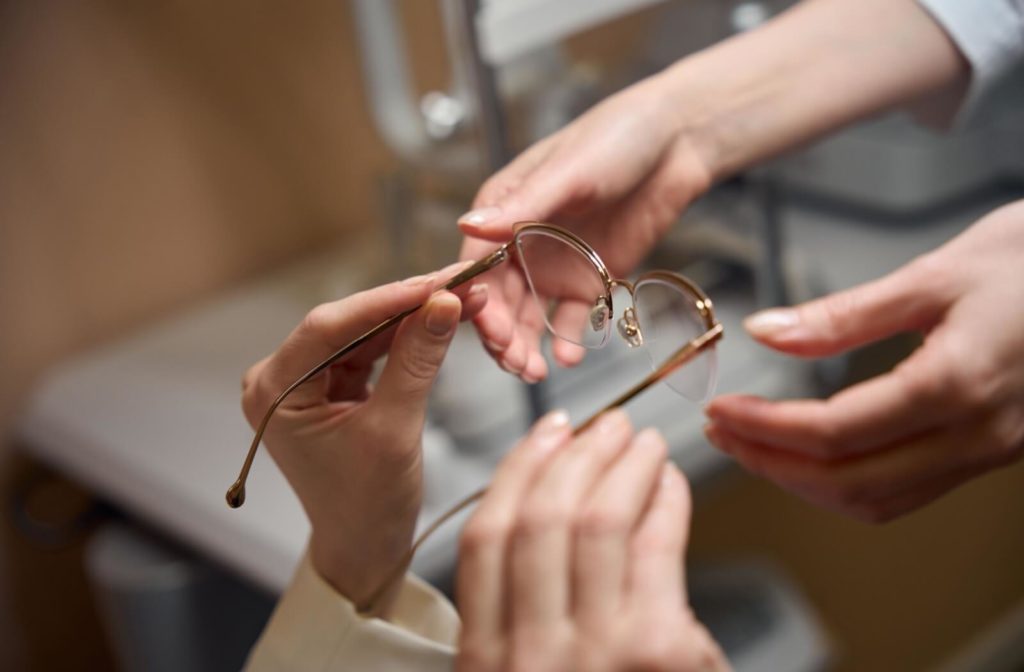 Optometrist passing glasses to a client.